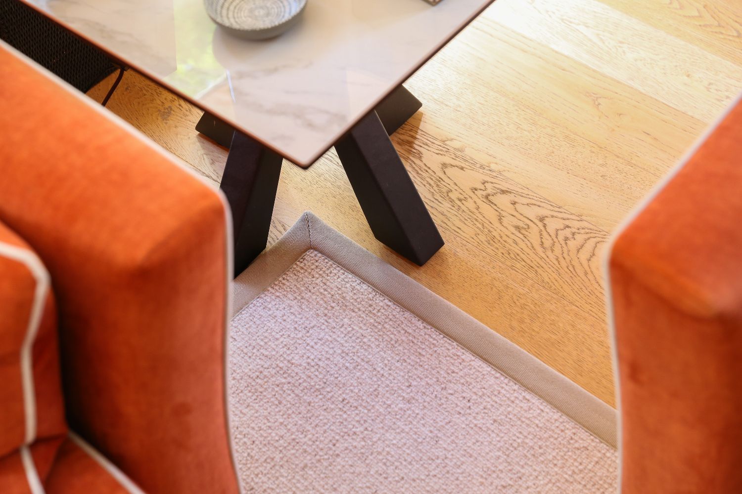 Oak wood flooring with a bordered carpet rug in a dining area